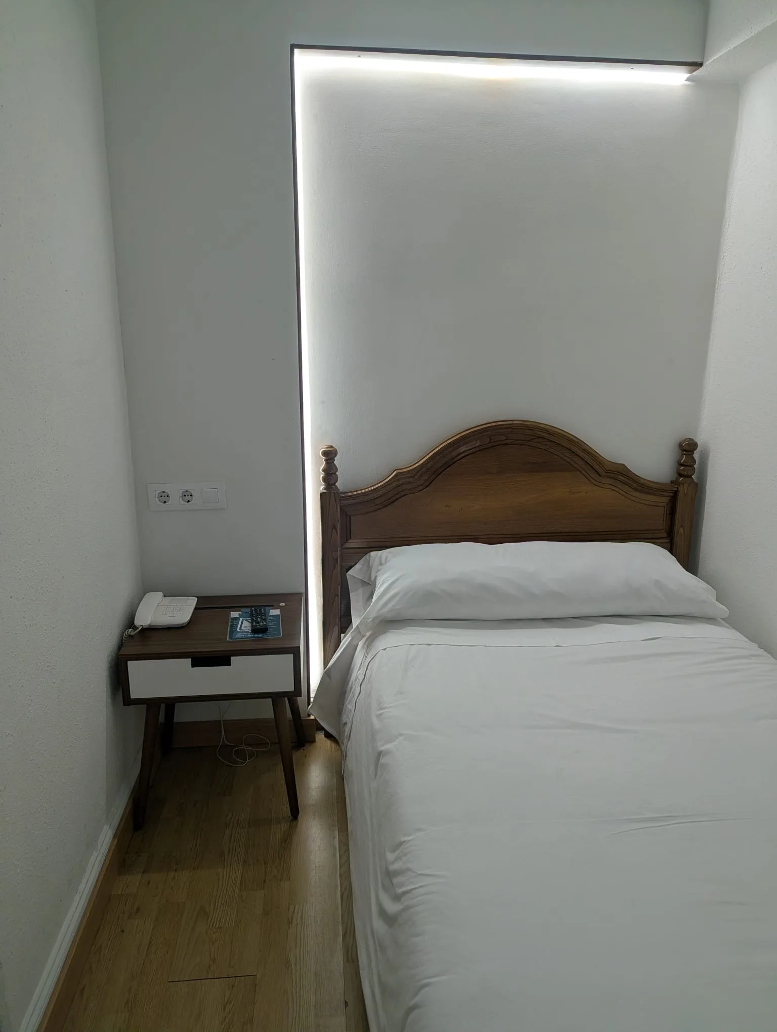 Habitación individual clásica de Hostal La Mexicana Santander con cabecero de madera tallada e iluminación LED de nicho