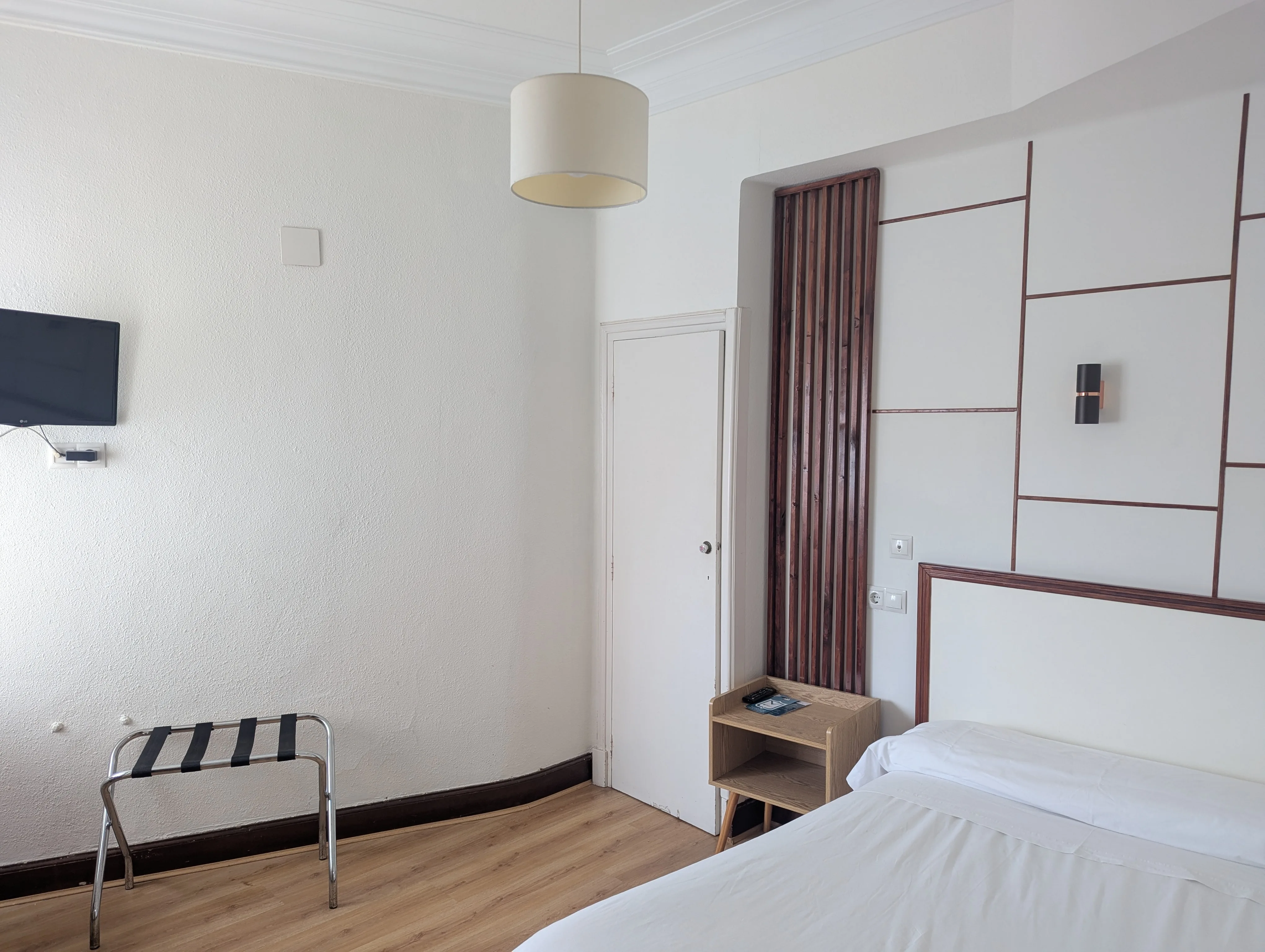 Vista general de habitación individual renovada en Hostal La Mexicana Santander, con Smart TV, separador de bambú y panelado geométrico